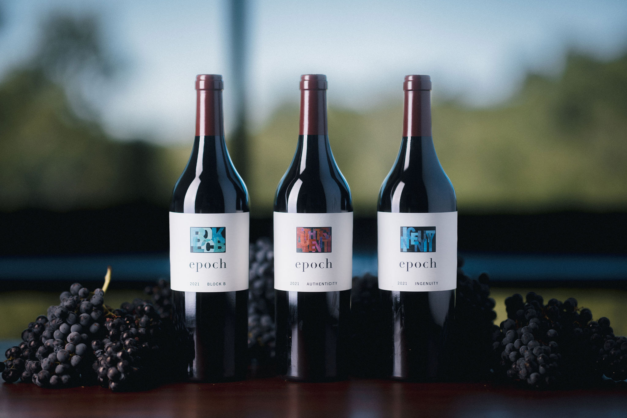 Three bottles of Epoch wine surrounded by grapes
